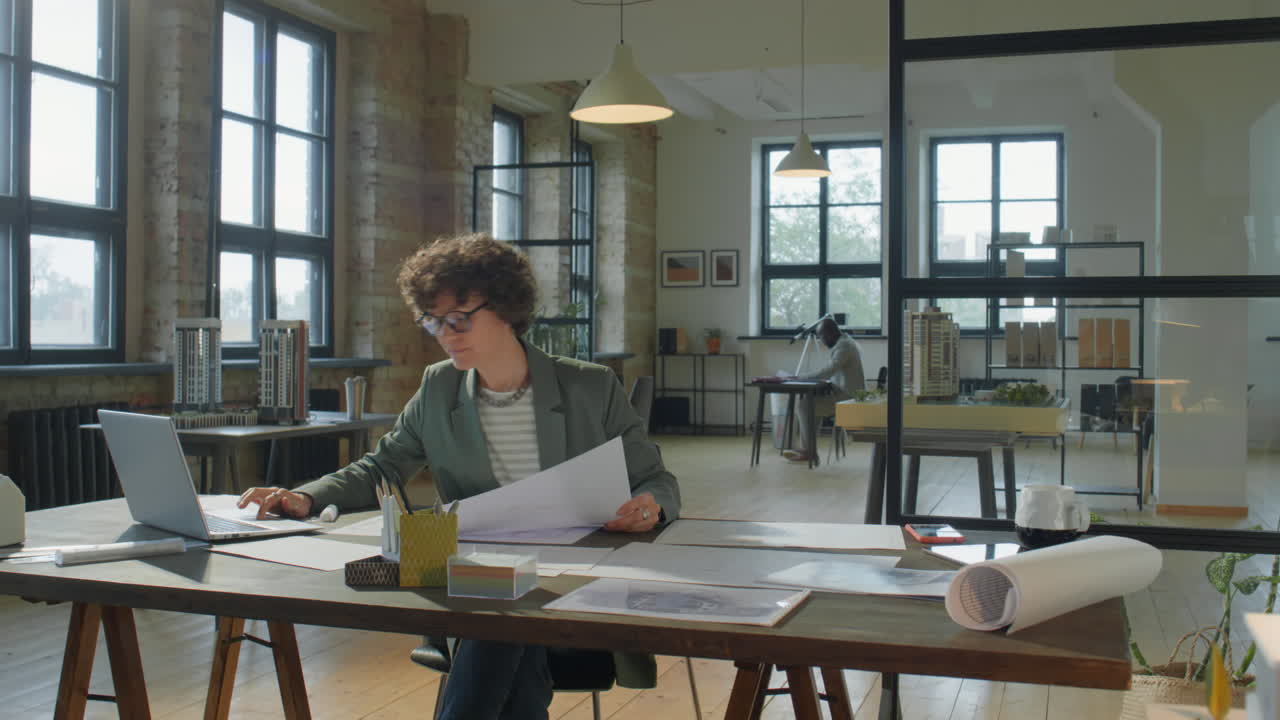 Architetta che esamina planimetrie in un moderno studio di progettazione
