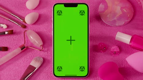 pink makeup flatlay with green screen phone