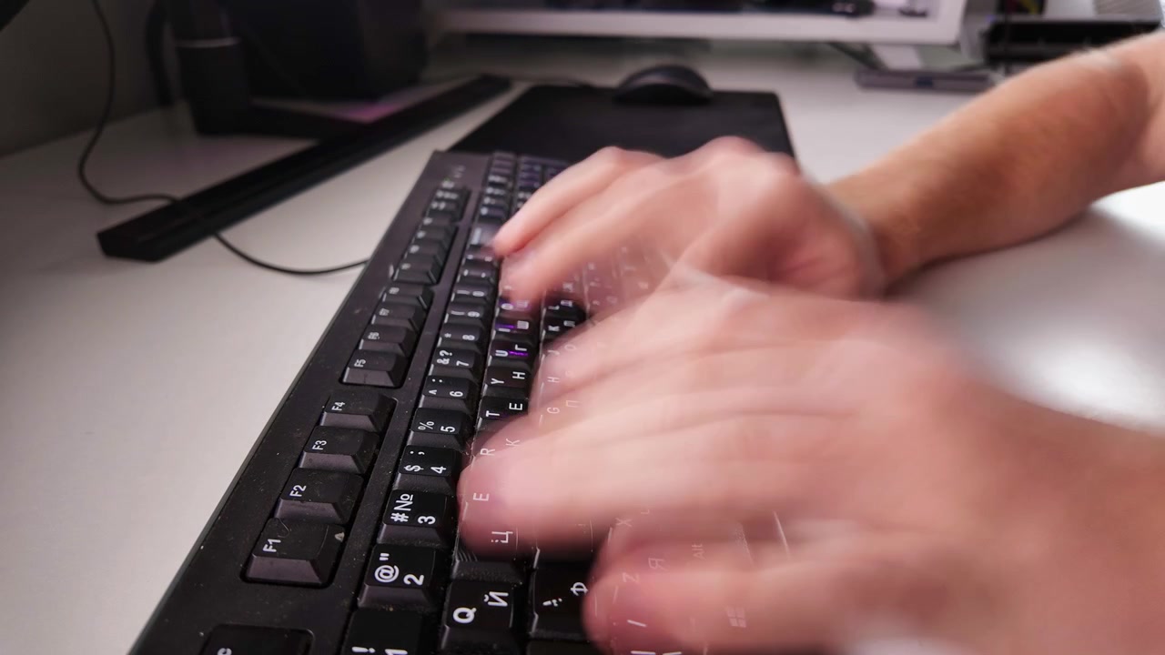 Man working at computer desk using keyboard and mouse in fast paced timelapse
