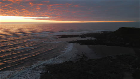 establishing aerial drone shot of cleveland way in scarborough at sunrise at low tide