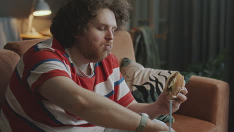 man eating a burger at home