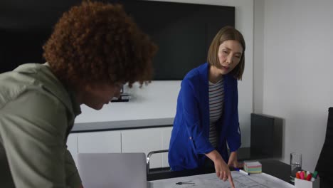 diversos colegas de negocios masculinos y femeninos en discusión en el trabajo mirando dibujos técnicos