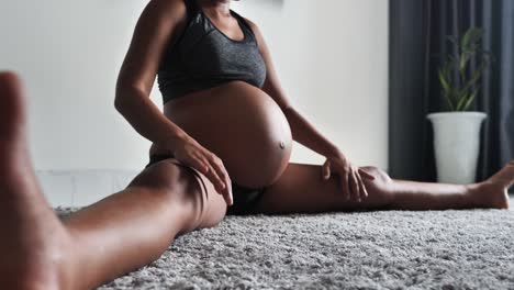 pregnant woman on third trimester doing stretching exercises at home.