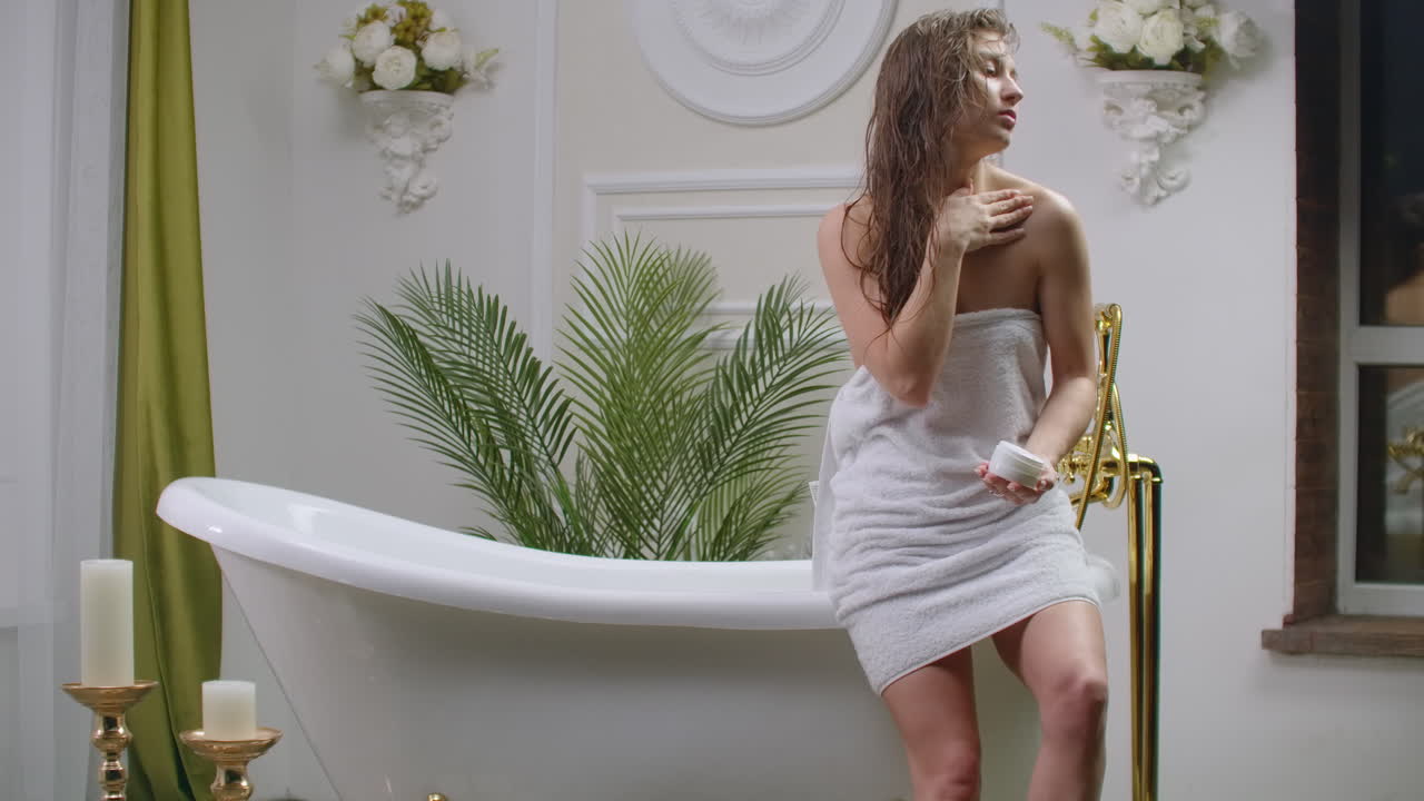 Young woman applying body lotion at morning. Close up of woman body care at home. Portrait of woman applying moisturizer cream on neck. Natural skin care.