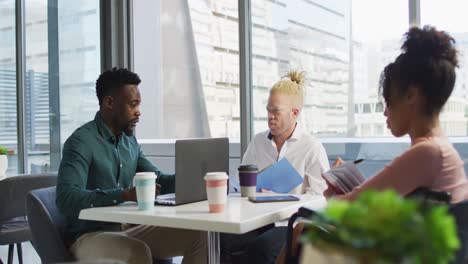 diverse business people discussing with disabled colleague and documents in creative office