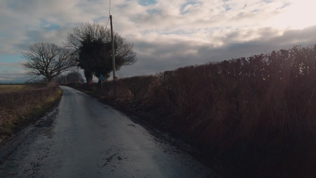 POV shot road riding a road bike cycling on sunny wet country lane in England
