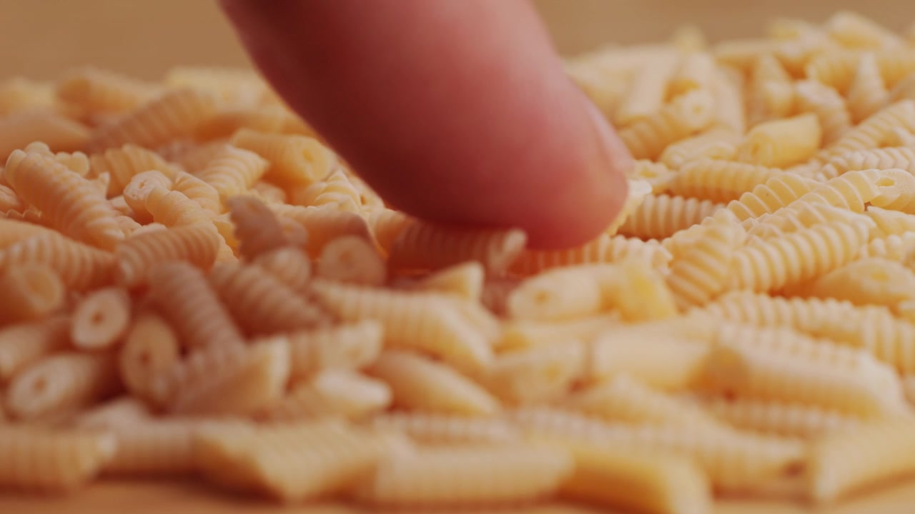 Primo piano di un dito che muove la pasta secca