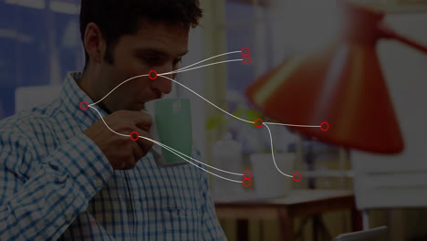 Man sipping mug at desk in home office, with animated financial charts, data emerging on tablet
