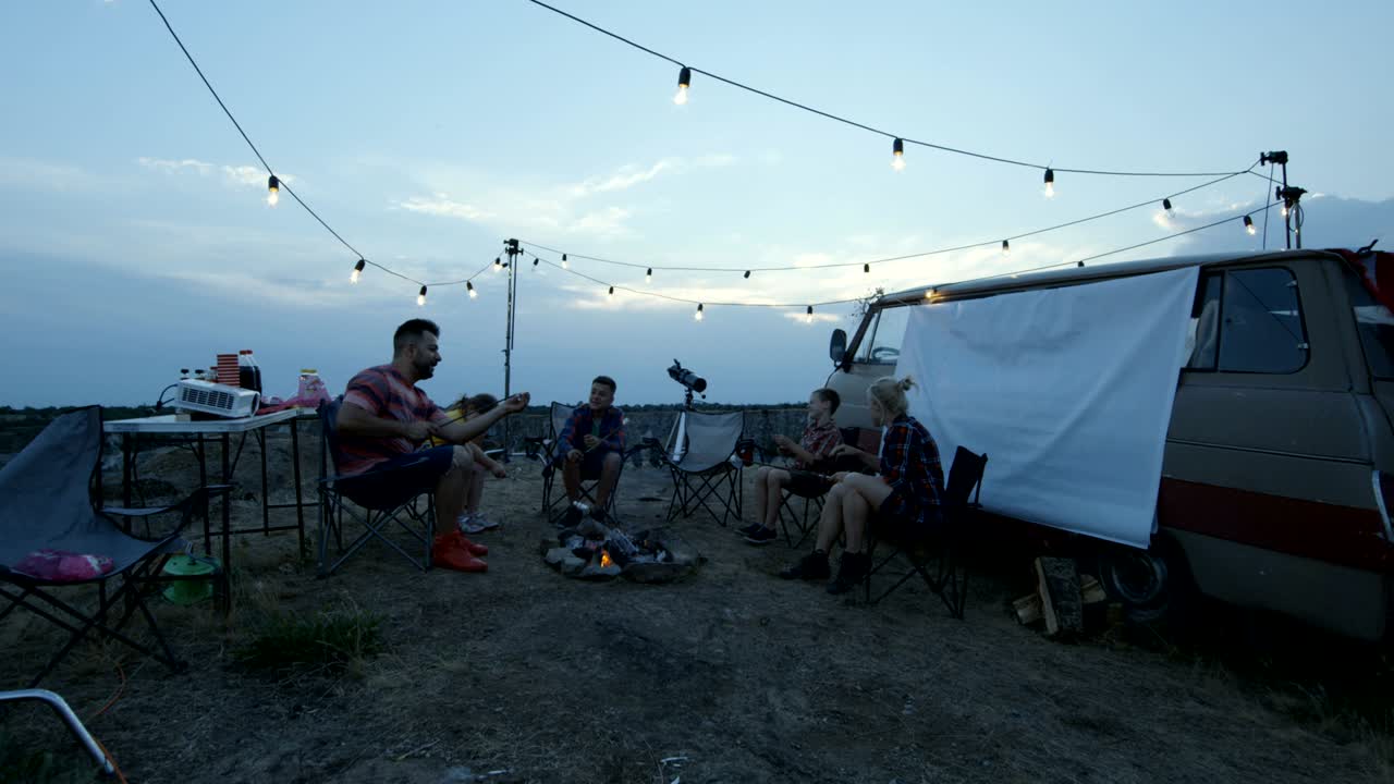 Laughing family frying marshmellow on bonfire