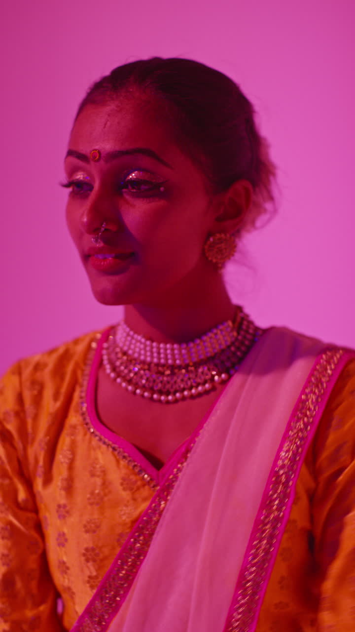 Vertical Video Head And Shoulders Studio Shot Of Female Kathak Dancer Performing Dance Wearing Traditional Indian Dress Against Purple Background 1