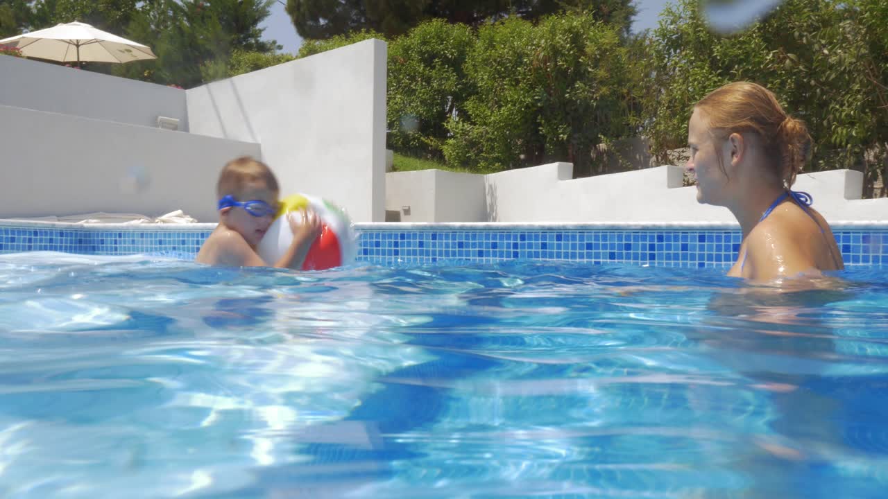 madre e hijo jugando con la pelota en la piscina