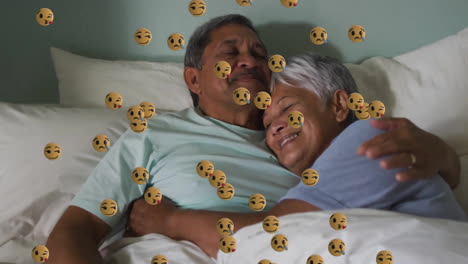 Animación-De-íconos-Emoji-Sobre-Una-Pareja-Birracial-Mayor-Abrazándose-En-La-Cama.