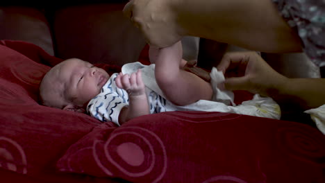 tranquilo adorable bebé recién nacido siendo limpiado por la madre mientras se acuesta en el sofá