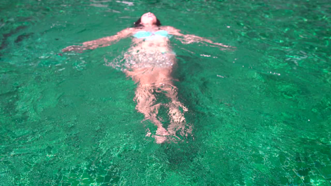 mujer nada de espaldas en la piscina al aire libre