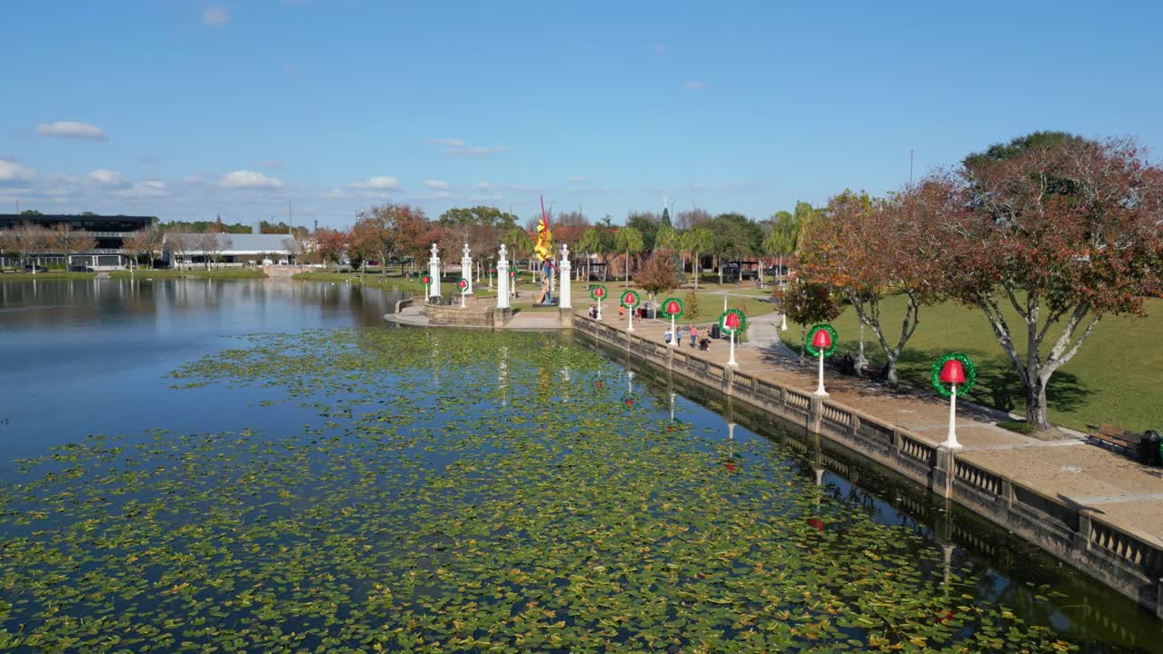 사람들은 연휴 기간 동안 플로리다주 레이크랜드의 호수 옆 가로등 기둥에 있는 크리스마스 장식을 지나 걷는다