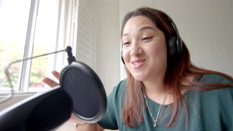 happy plus size biracial woman in headphones podcasting at home, copy space, slow motion