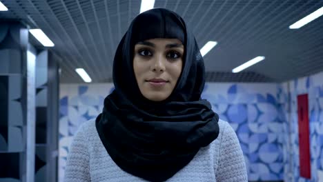 young muslim woman in hijab is standing in underpass, watching at camera, religion concept