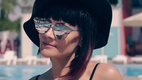 hot brunette girl sits in summer on beach in deck chair in sunglasses with mirror glasses