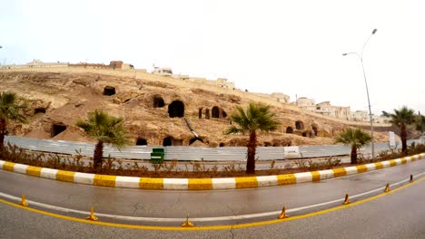 cars drive in front of camera empty anciant cave city in centre of urfa