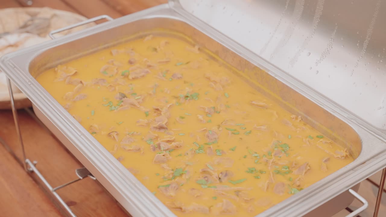 Close up of Portuguese bifanas in rich sauce on stainless buffet tray