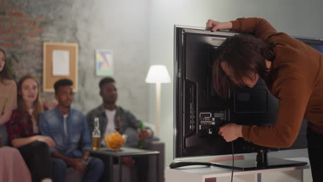 man fixes broken tv to watch football game with friends