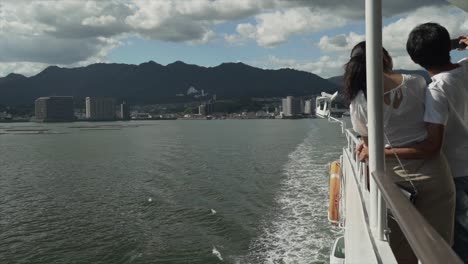 a beautiful scenic view of an asian couple on a ship at sea taking a selfie together