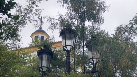 Escena-Fija-De-Una-Iglesia-En-España,-Capturando-Luces-De-La-Calle-Con-Ramas-De-árboles-Frente-A-La-Vista-De-La-Iglesia