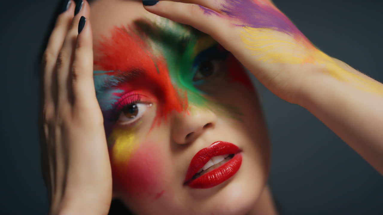 retrato de cerca mujer atractiva con cara pintada de colores exótico arte corporal multicolor sensual mujer que disfruta de la expresión creativa