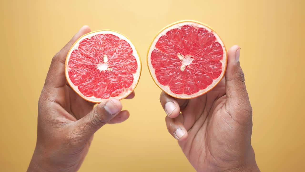 Hands holding two halves of a grapefruit