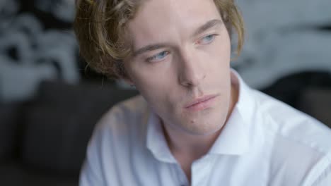 close-up of a thoughtful young man in a white shirt.