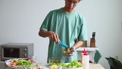 young man preparing a fresh salad in the kitchen