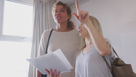 two female friends buying house for first time looking at house survey in room to be renovated