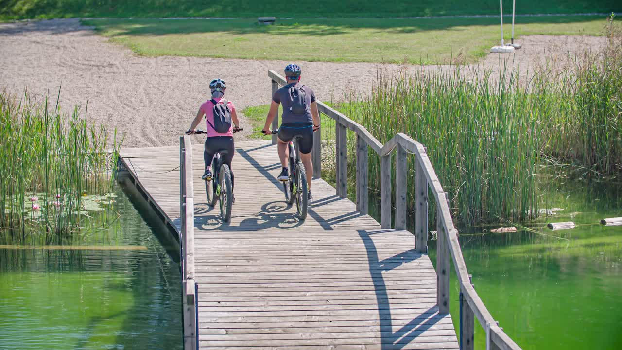 Follow shot of people cycling over a wooden path on the water. Cycling adventure. Slovenia