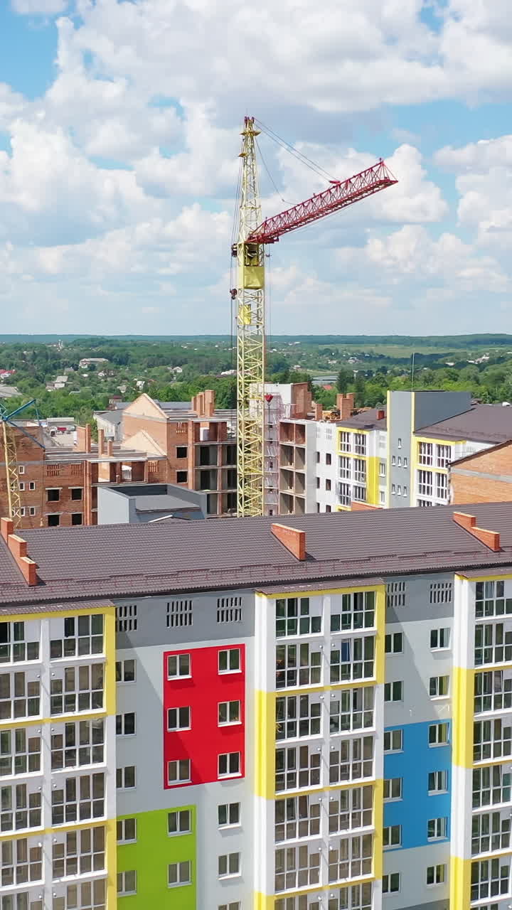 Construction site of a modern district. Tower crane build new high-rise buildings on nature background. Residential complex is building. Drone view. Vertical video