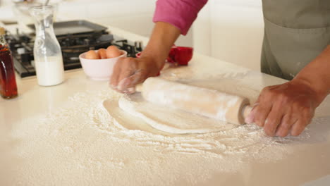 rolling dough with rolling pin, man preparing homemade pizza in kitchen