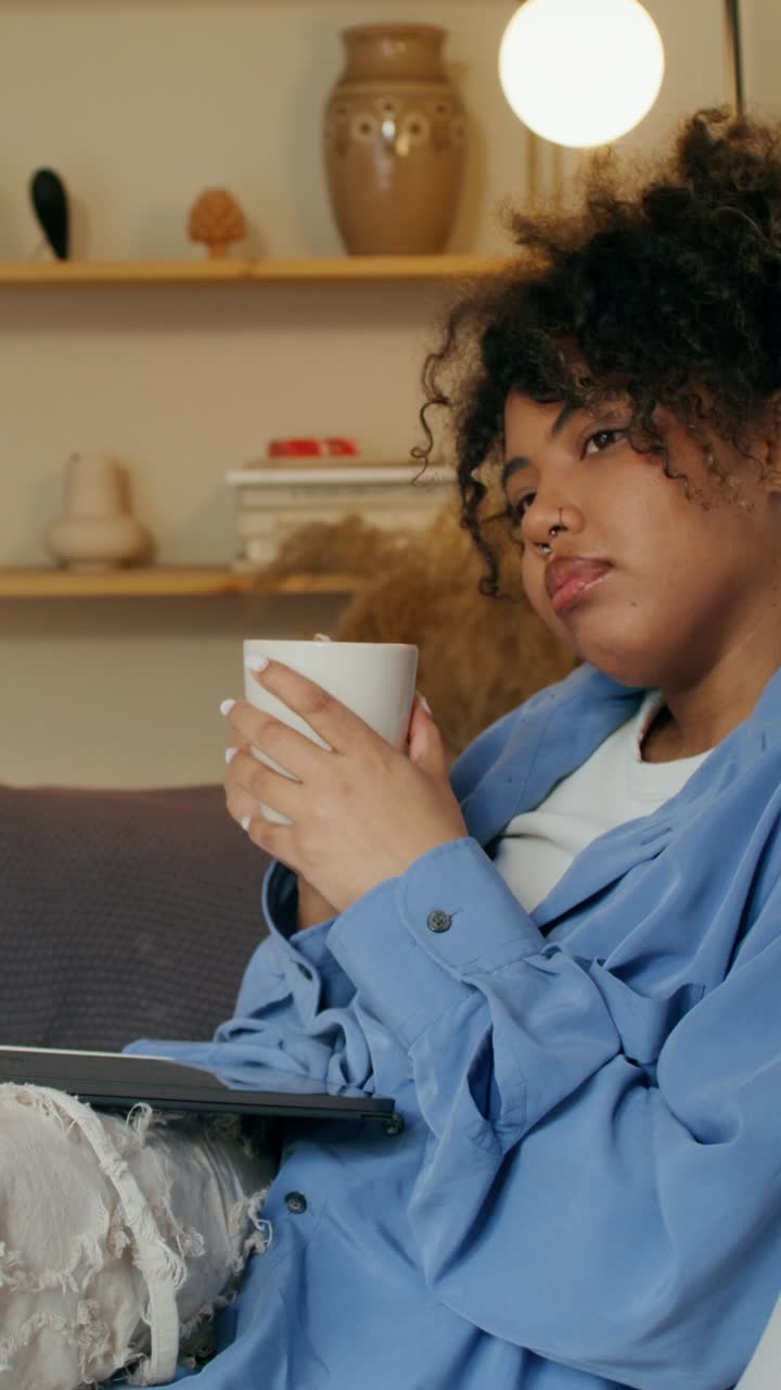 Kvinde slapper af hjemme med bærbar computer og kaffe