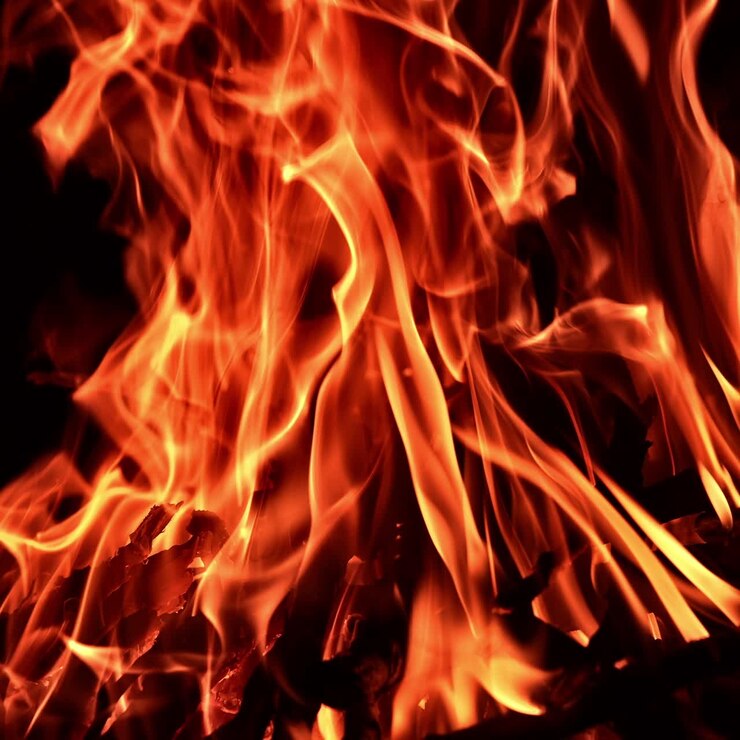 Hoguera hipnótica ardiendo en la oscuridad de la noche. Trozos de madera quemándose en la fogata.