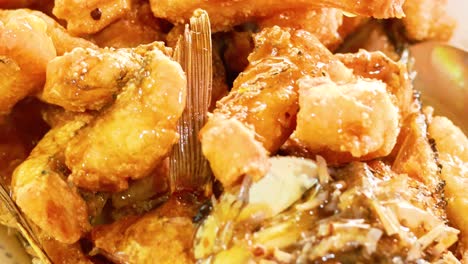 primer plano de pescado frito crujiente en una rica salsa, mostrando textura y tonos dorados en un entorno culinario vibrante