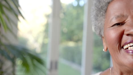 Half-portrait-of-happy-senior-african-american-woman-laughing-in-sunny-room,-copy-space,-slow-motion