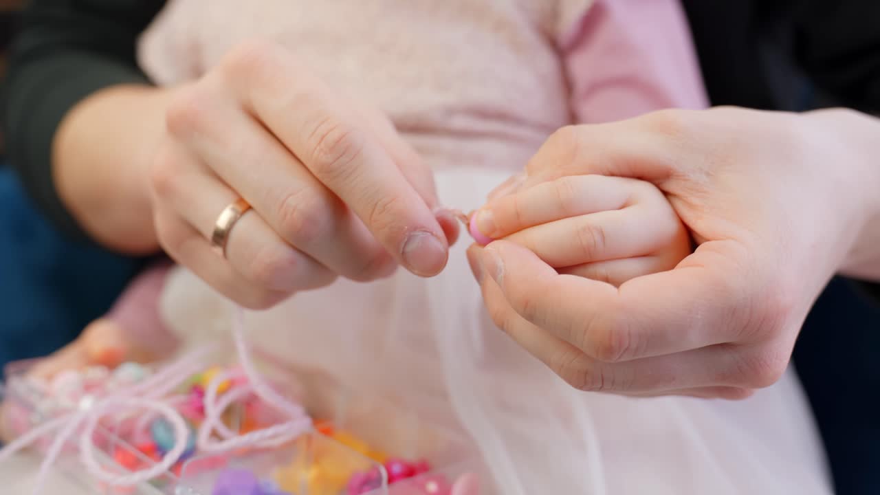 Female toddler hands arranging beads for custom necklace in home setting
