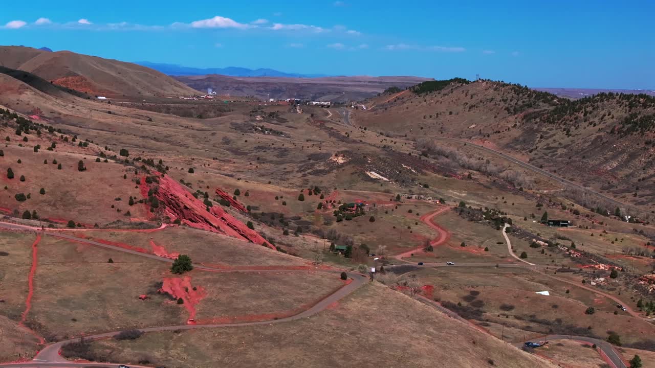 Morrison Golden i70 Colorado Red Rocks Park and Amphitheater bike hike trails aerial drone view cars front range foothills neighborhood dry mid winter sunny blue sky clouds parallax right motion
