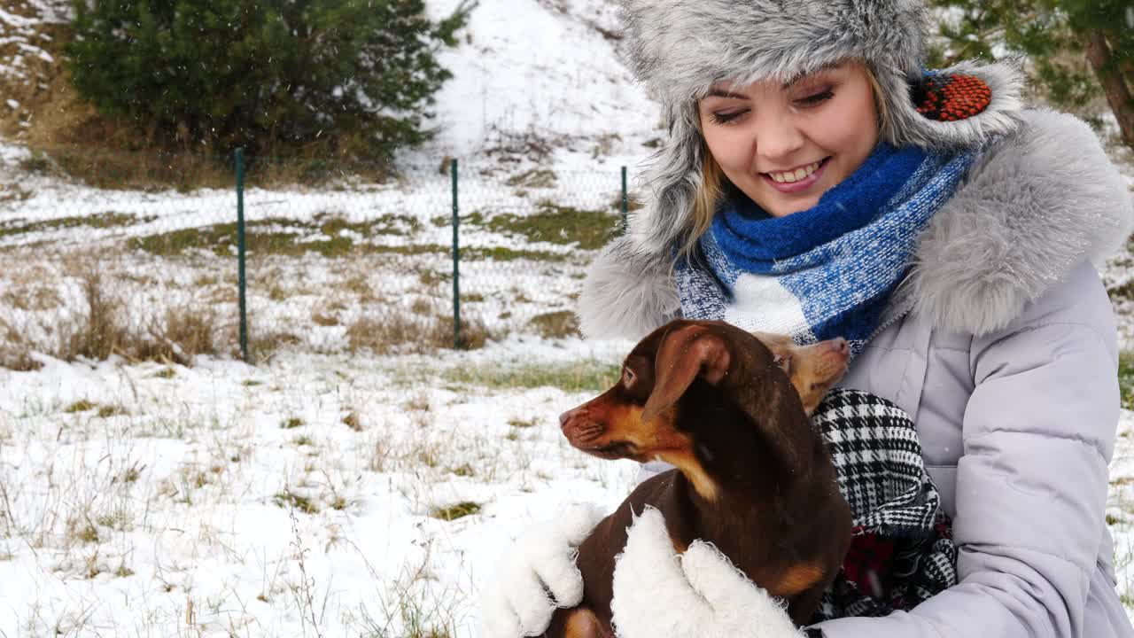 여자 는 겨울 밖 에서 작은 개 와 함께 놀고 있다