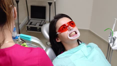 Mujer-Joven-Con-Un-Expansor-En-La-Boca-En-La-Clínica-Dental.-Aplicación-De-Gel-Blanqueador-En-Los-Dientes.-Consultorio-Dental-Moderno.-Filmado-En-4k