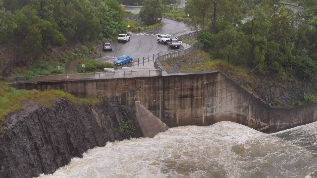 Handheld shot of Hinze Dam viewing carpark under heavy rain and water flows during La Ni&ntilde;a, Gold Coast Hinterland, Queensland, Australia