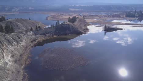 eroded sandy hills crumble into deep blue water of mountain wetland