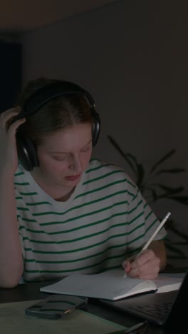 una adolescente estudiando hasta tarde en la noche.