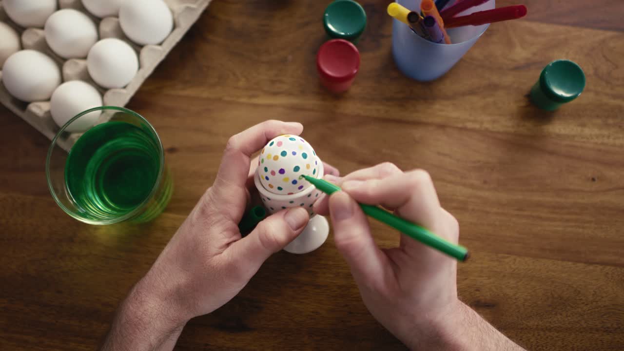 Detail of human hands decorating easter eggs with a felt-tip pen.