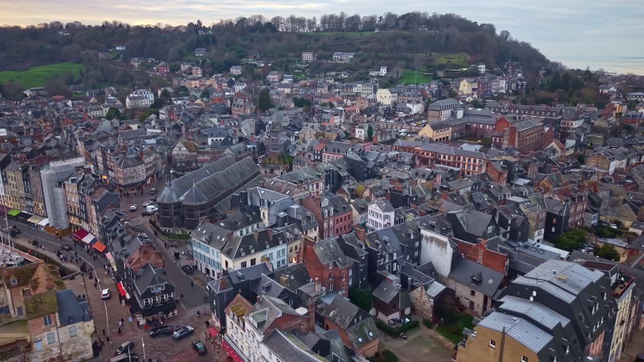 Fransa'nın Honfleur kasabasında, koyu arduvaz çatılı, ahşap iskeletli, beyaz sıvalı yarı ahşap binaların yoğun kümesi, kendine özgü ahşap Église Sainte-Catherine kilisesini gözler önüne seriyor, drone yörüngede dönüyor.