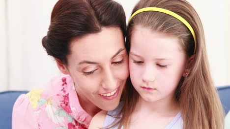 mother and her daughter reading a book on couch