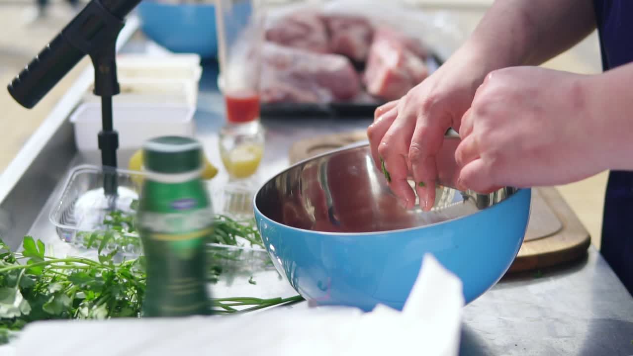 Man is mixing meat pieces with spices and honey in metal bowl. The wooden surface outside. Barbeque time. shot in 4k